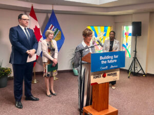 Image of Leslie Allen, CEO of WIN House, speaking at a podium at a government announcement event.